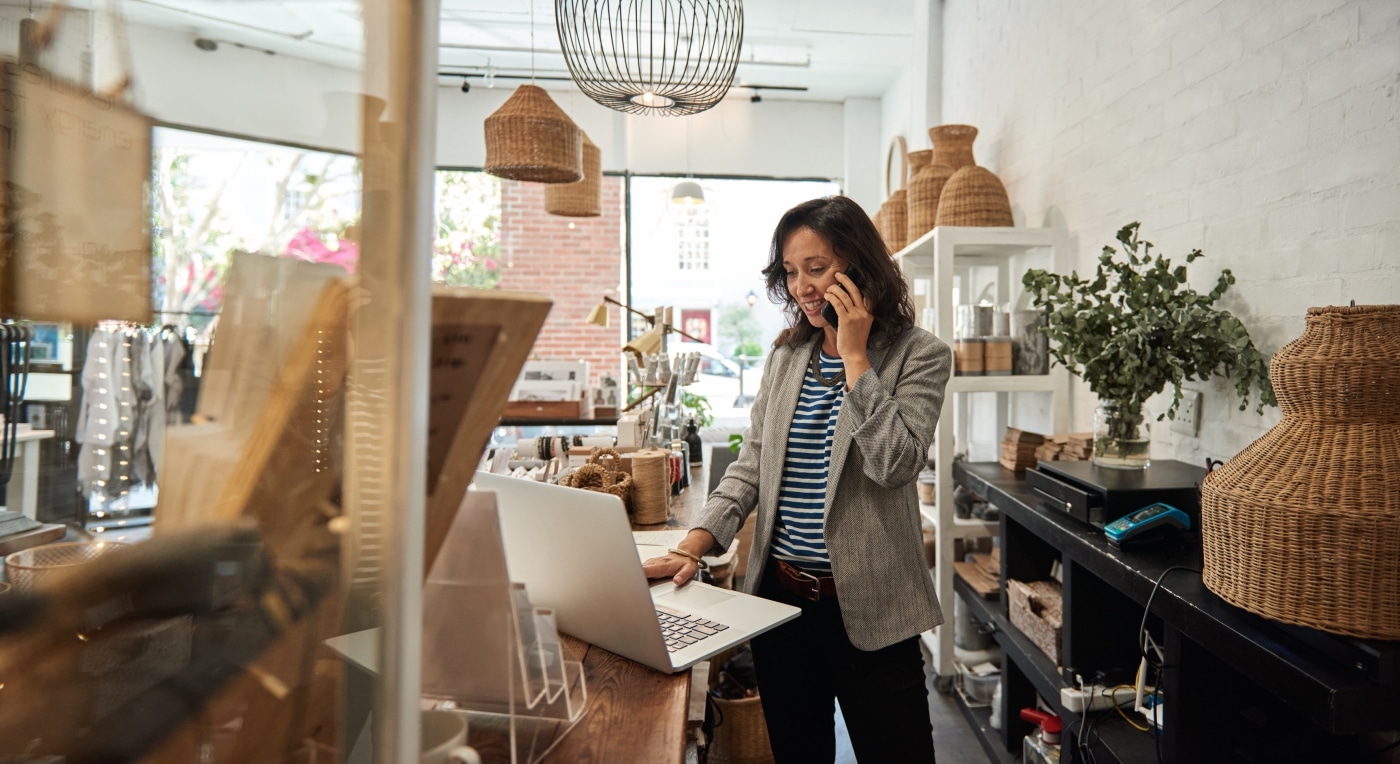 Woman calling on the phone while looking at laptop in front of her