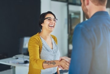 Woman shaking hands in office smiling