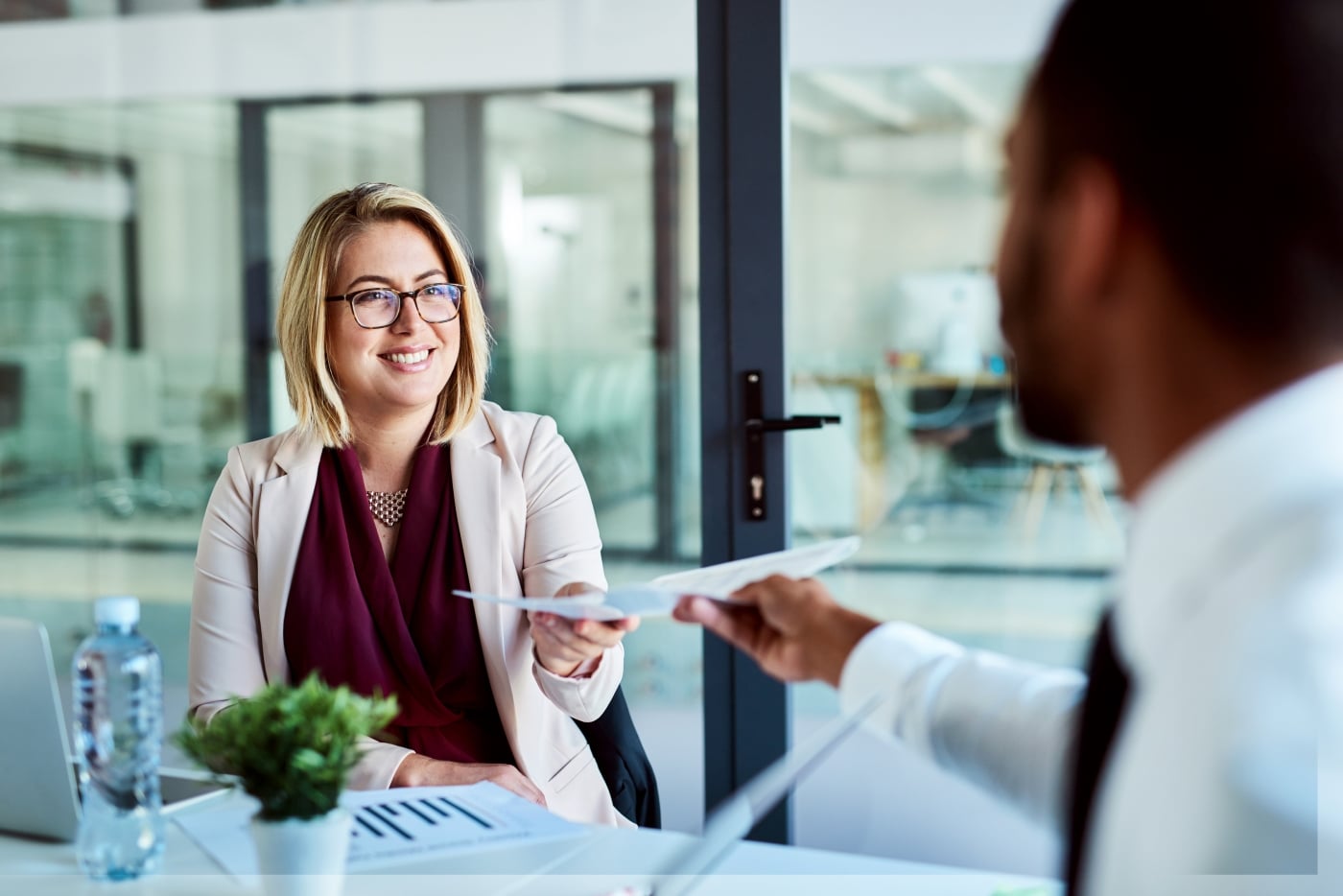 Woman getting handed a document and smiling