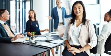 Businesswoman smiling at a camera with diverse colleagues in the background