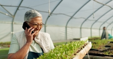 Woman on phone call laughing in greenhouse