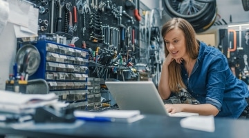 Woman in tool house looking at laptop