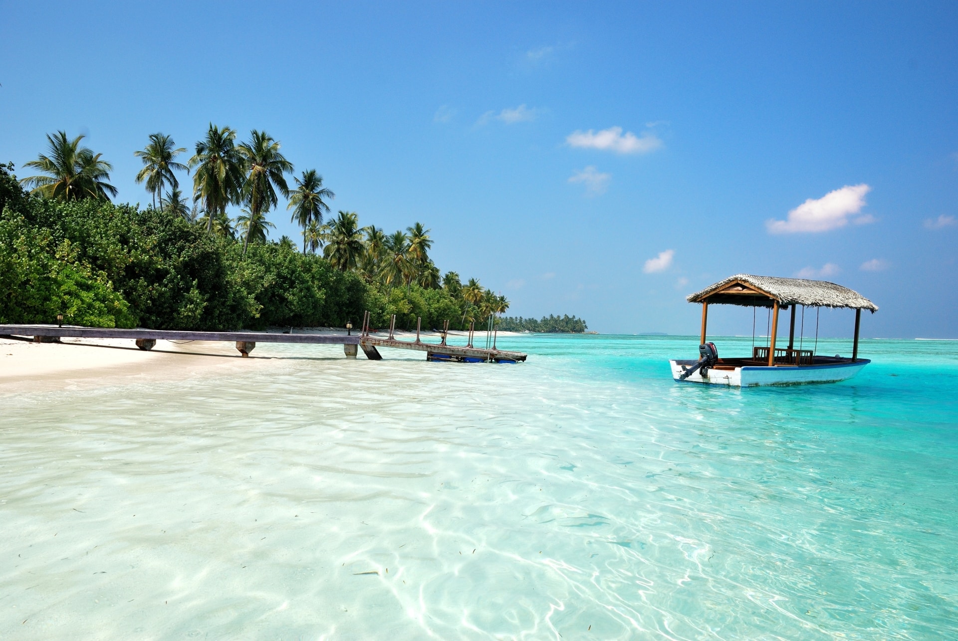 A beautiful white beach, green tropical trees and dazzling turquoise blues of the sea. A beautiful holiday scene